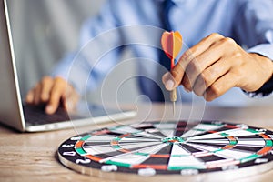 Businessman holding a darts aiming at the target center business goal concept - business targeting, aiming, focus concept,metaphor