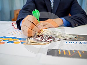 Businessman holding a darts aiming at the target center of dart board, Setting challenging business goals And ready to achieve the