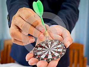 Businessman holding a darts aiming at the target center of dart board, Setting challenging business goals And ready to achieve the