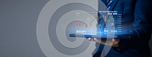 Businessman holding a device with a stock chart hologram, investing, using technology to invest in stocks. The concept of using