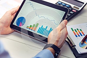 Businessman holding digital tablet with graphs and charts report