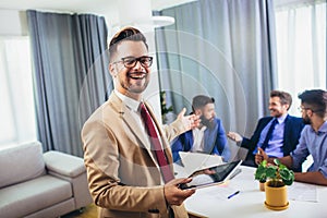 Businessman holding digital tablet in modern office with businessmen working at the background