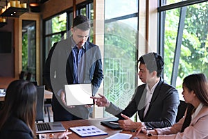 Businessman holding digital tablet and presenting new project to business partners in conference room.