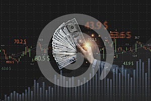 Businessman holding dollar banknote with stock market graph and up arrow for inflation and interest rating increasing concept