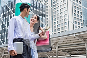 Businessman holding dollar cash with laptop and asian woman hold