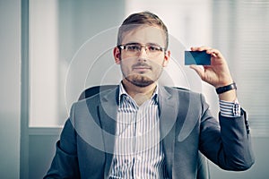 Businessman holding empty business card in the office