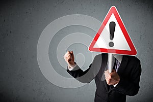 Businessman holding an exclamation road sign