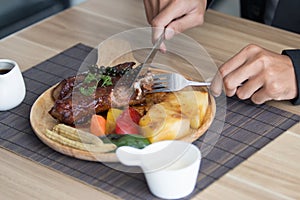 Businessman holding fork and knife eating steak.