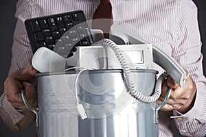 Businessman Holding Garbage Can With Obsolete Office Equipment