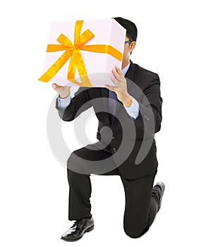 Businessman holding a gift box and kneel.