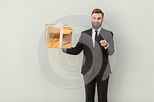 Businessman holding gift box, pointing fingers at camera and smiling