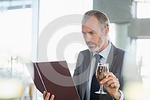 Businessman holding glass of beer and looking at menu