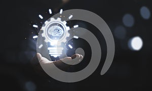 Businessman holding glowing drawing lightbulb with virtual brain and connection line, creative thinking ideas and innovation