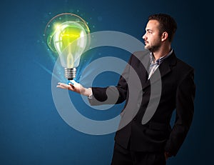 Businessman holding glowing lightbulb in his hand