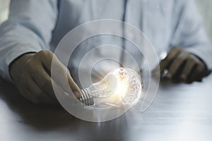 Businessman holding glowing lightbulb and using computer laptop to input business strategy idea , creative thinking ideas and