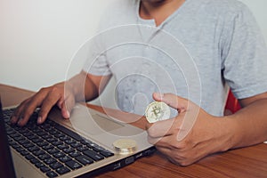 Businessman holding a gold Bitcoin on a laptop. Make money with bitcoin, digital currency money investment concept, blockchain