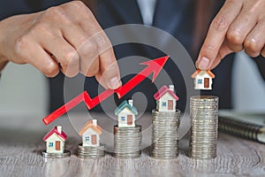 Businessman Holding  Graph Over The Increasing House Miniature, Real estate investment,investment mortgage finance and home loan
