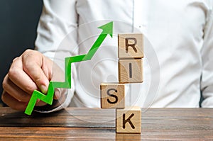 Businessman holding a green up arrow near the word Risk. Improving business resilience, reducing risks and costs. Development