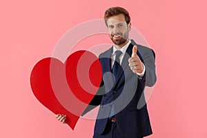Businessman holding a heart shape and giving a thumbs up