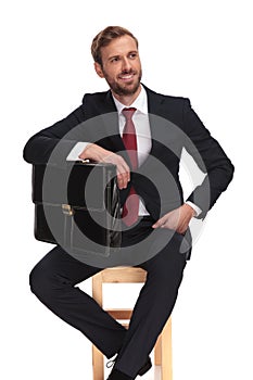 Businessman holding his suitcase under his elbow looks to side