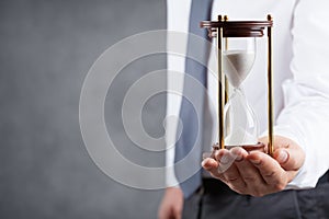 Businessman holding hourglass in his hand. Deadline and time management concept.