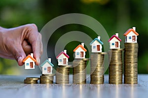 A businessman holding a house style placing on a pile of coins The concept of real estate growth Investment and risk management.