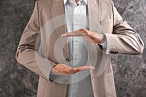 Businessman holding imaginary clock on grey background. Time management concept