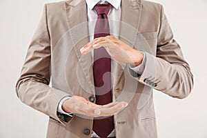 Businessman holding imaginary clock on light background. Time management concept