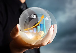 Businessman holding increasing graph in crystal ball photo