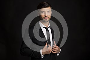 Businessman Holding Jacket Lapels Looking At Camera Standing, Black Background