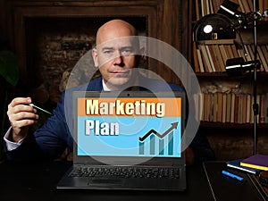 Businessman holding a laptop. Business concept about Marketing Plan with phrase on the sheet