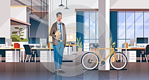 Businessman holding laptop creative office coworking center room interior modern workplace desk bicycle ecological