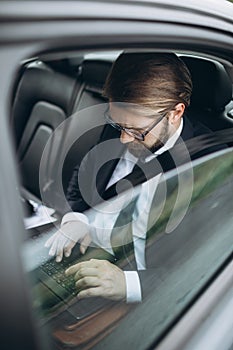 Businessman holding laptop on knees while driving car