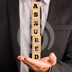 Businessman Holding Letter Blocks Spelling Assured