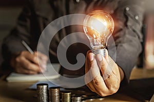 businessman holding light bulb with money stack.saving energy power concept