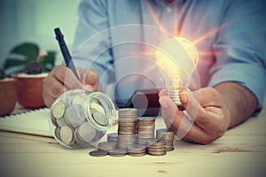 Businessman holding a light bulb, right-hand recording accounts, expenses, and profits.