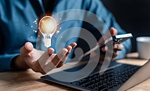 Businessman holding light bulb using computer for creative thinking idea creativity to making money to wealth concept