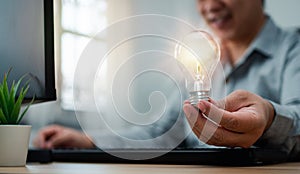 Businessman holding lightbulb and feeling happy by new innovation and ideas for success business panels. Concept of innovation