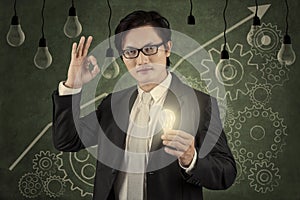 Businessman holding lightbulb with upward graph 2