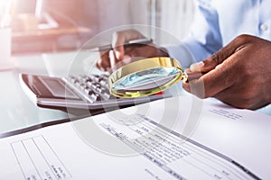 Businessman Holding Magnifying Glass Over Invoice