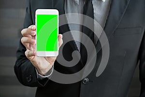 Businessman holding mobile smart phone with green screen