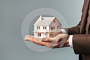 Businessman holding model house Close up. Loan, investment or Home insurance concept