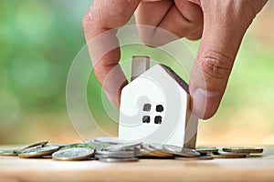 Businessman holding a model house model is placed on a pile of coins.using as background business concept and real estate concept photo