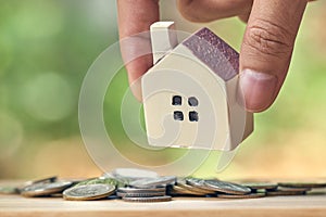 Businessman holding a model house model is placed on a pile of coins.using as background business concept and real estate concept photo