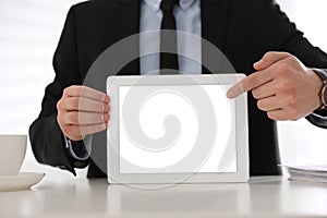 Businessman holding modern tablet with blank screen at table in office, closeup