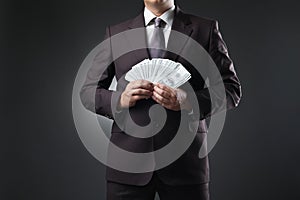 Businessman holding money in hands on dark