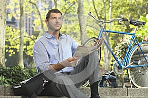 Businessman Holding Newspaper By Bicycle