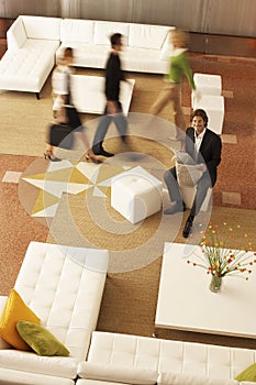 Businessman Holding Newspaper With Coworkers Walking In Office Lobby