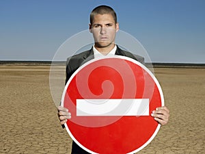 Businessman Holding 'No Entry' Sign In Desert