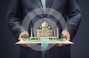 Businessman holding an open book with sketch of Taj Mahal on the top